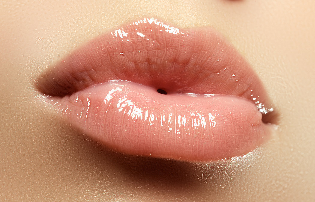 Glossy, pink lips close-up, with visible texture and shine.